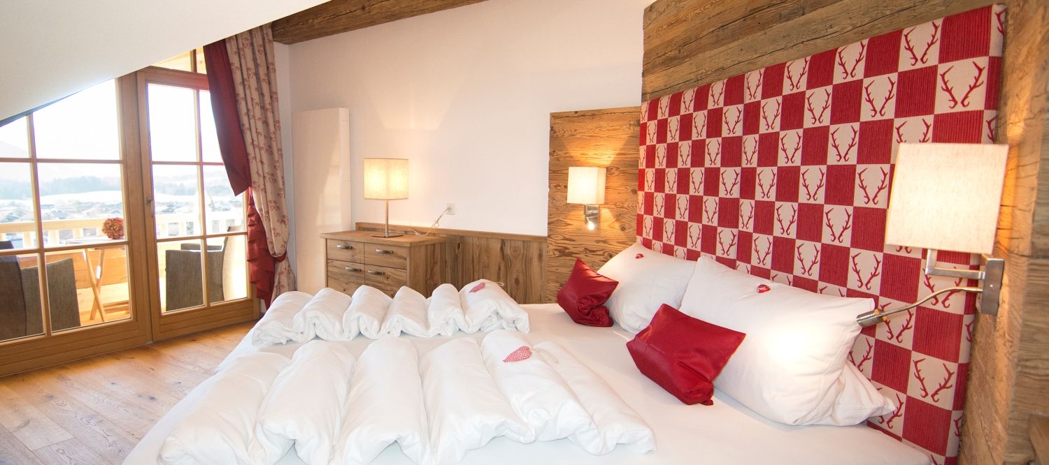 Schlafzimmer Ferienwohnung Kaiserwinkl Suite mit Altholz und Blick auf Balkon und Kaisergebirge in Reit im Winkl