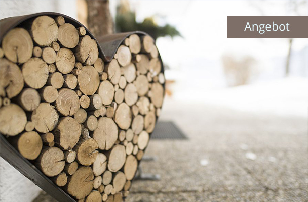 Herz aus Holzscheiten vor Haus von Ferienwohnungen Neumaier Reit im Winkl